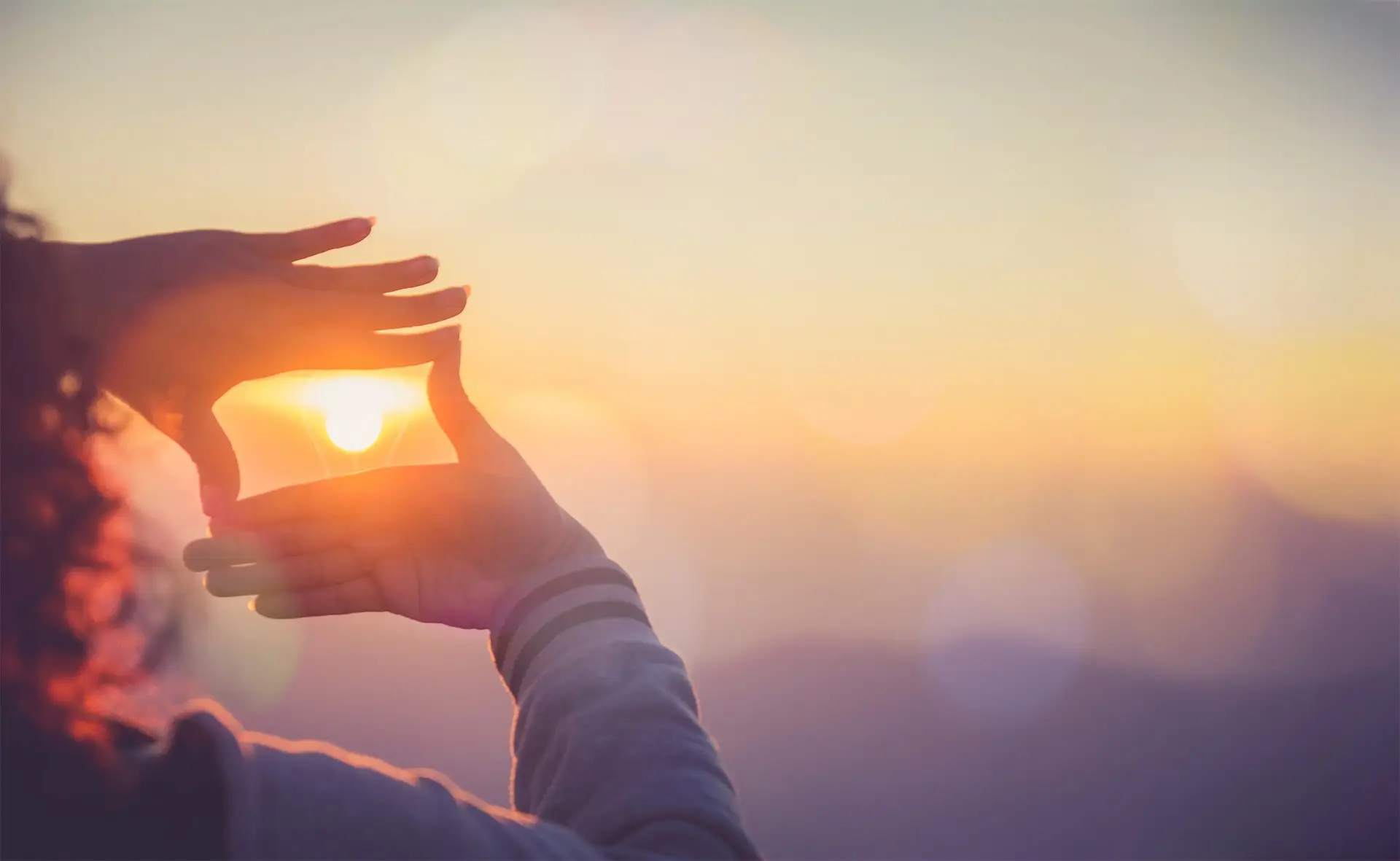 Hands framing the setting sun